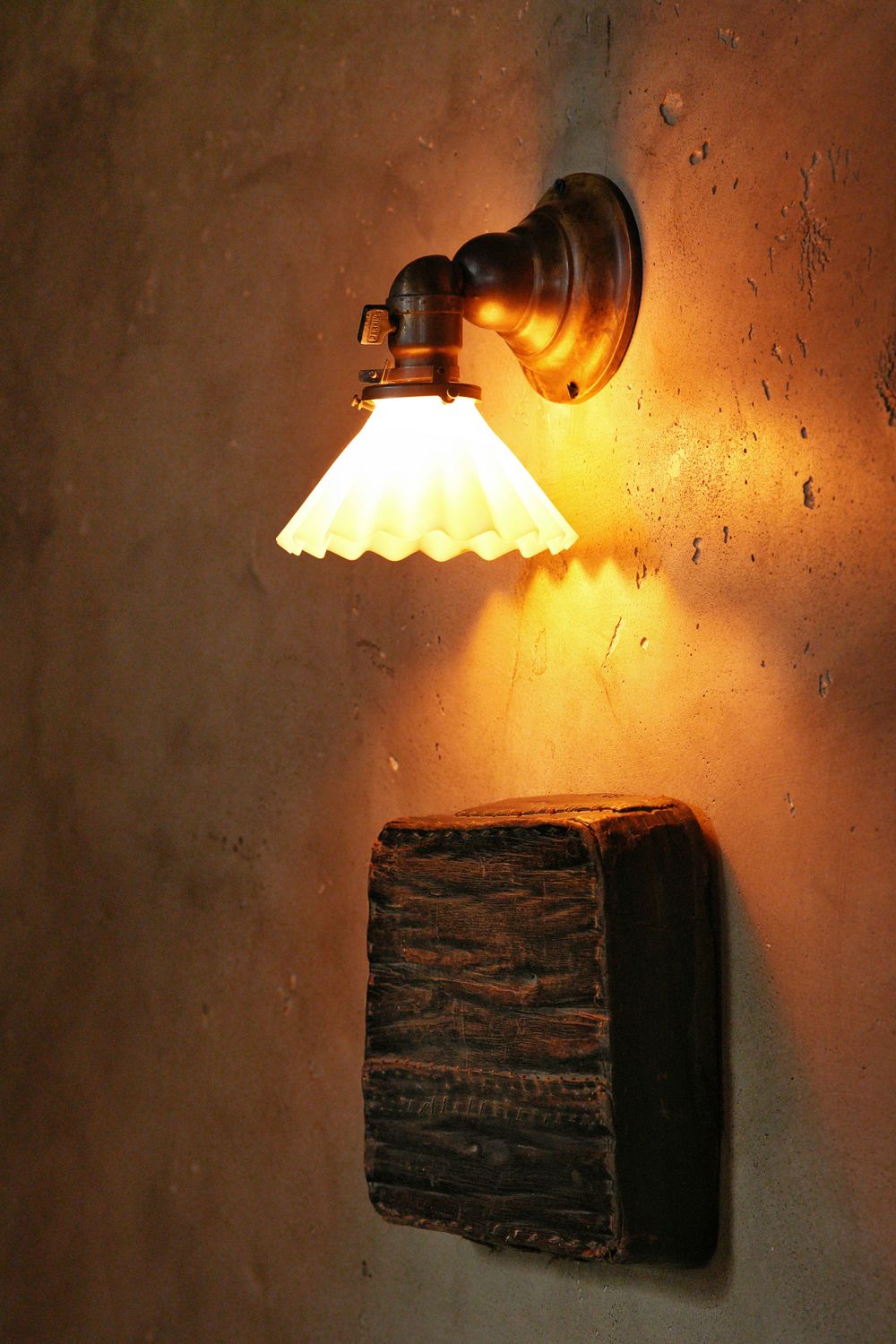 Pleated glass shade lighting a plaster wall — photo by yu xin on Pexels