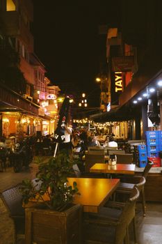 Captivating urban nightlife scene with outdoor diners and colorful lights on a bustling street.