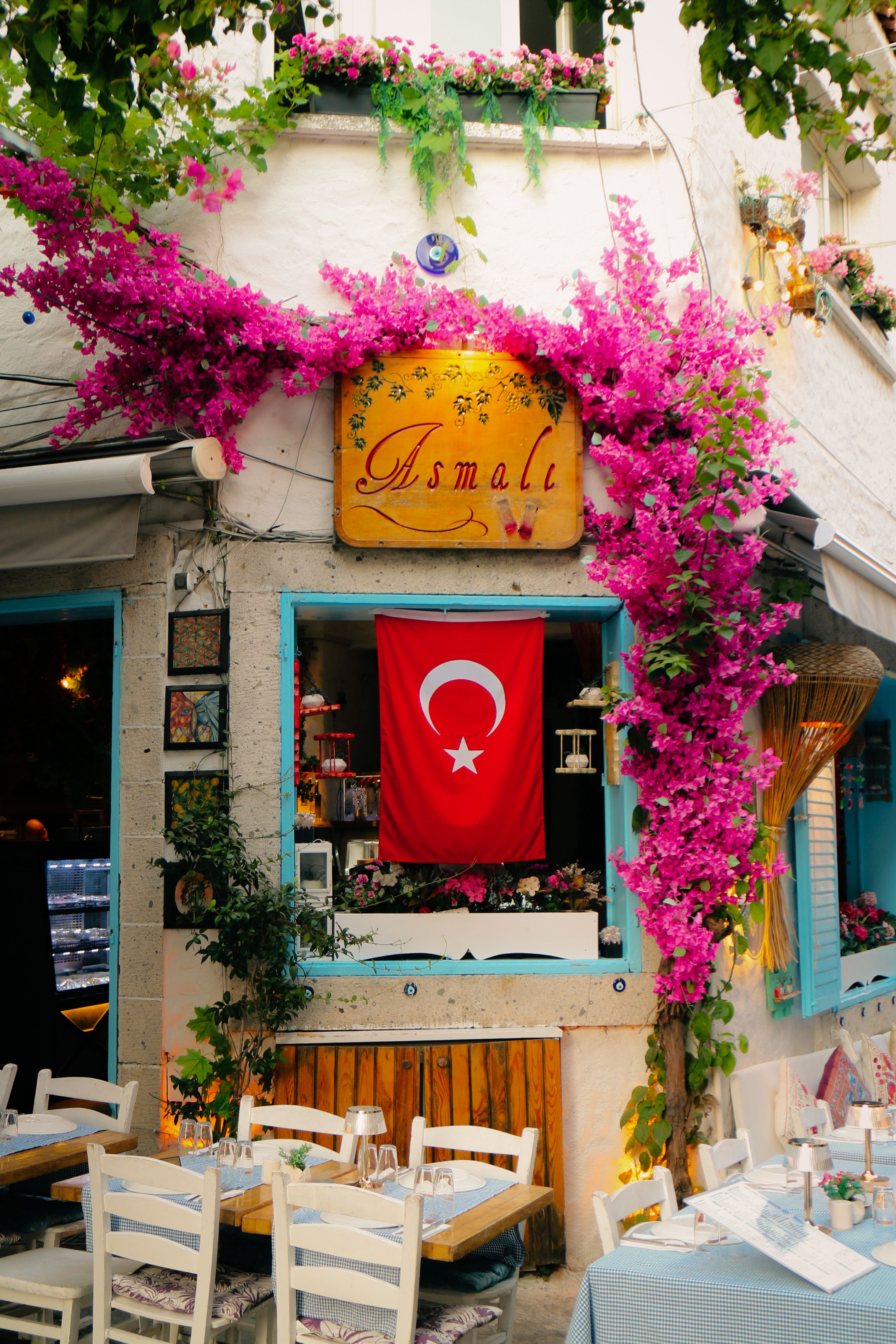 Quaint outdoor cafe in Turkey decorated with vibrant pink bougainvillea and Turkish flag.