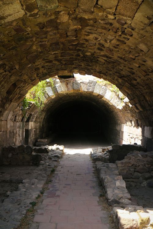 Free Sunlit entrance of an ancient stone tunnel with rustic arches and a mysterious dark interior. Stock Photo