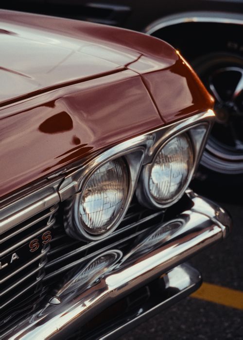 Free A close-up shot of a vintage red Chevrolet with prominent chrome details and headlight design. Stock Photo