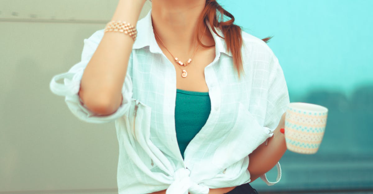 A young woman laughs while talking on the phone outdoors, holding a mug.