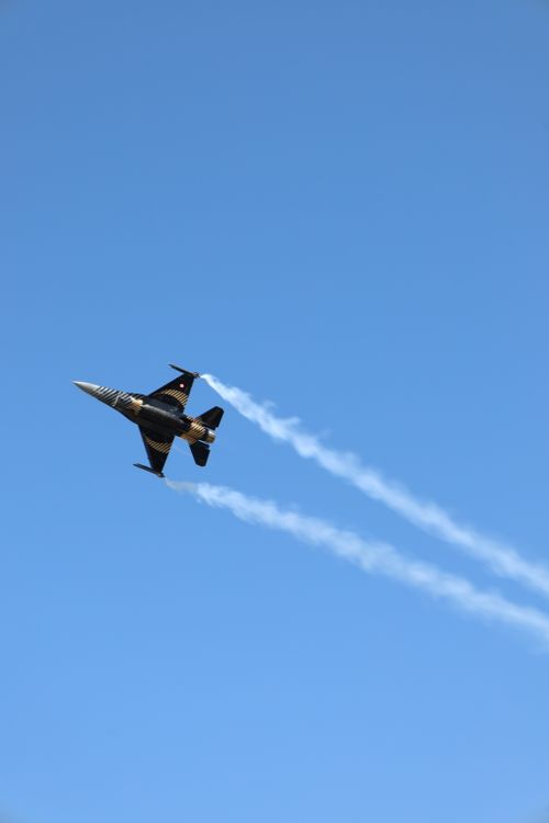 Free A sleek jet plane performs aerobatics over Ankara with clear trails against the blue sky. Stock Photo
