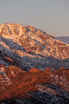 Scenic view of snow-capped mountains with warm sunset lighting.