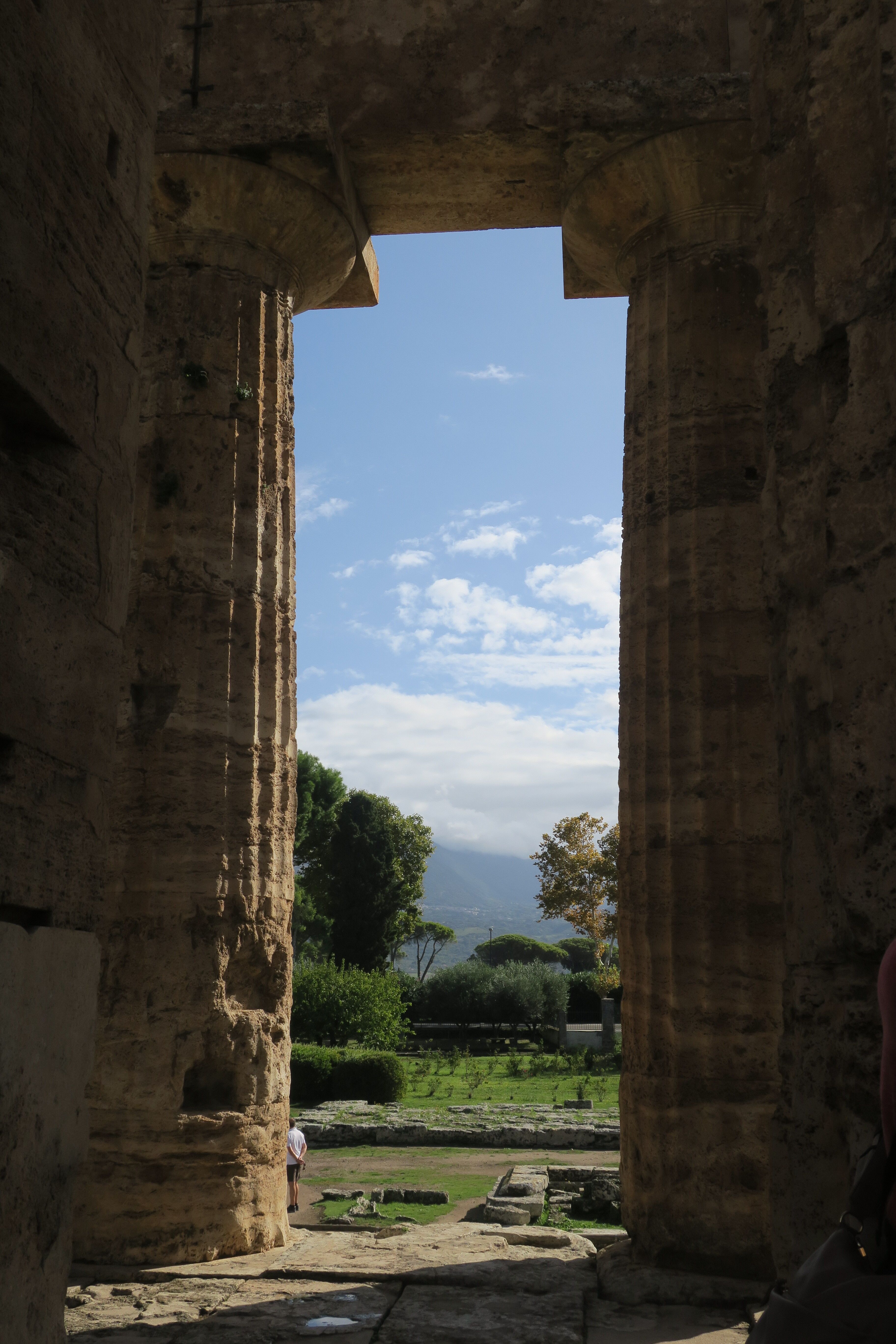 View through ancient temple columns in Paestum, Campania, Italy, capturing historical beauty.