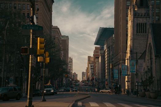 A bustling city street with traffic lights and pedestrians during the early evening.