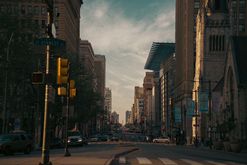 A bustling city street with traffic lights and pedestrians during the early evening.