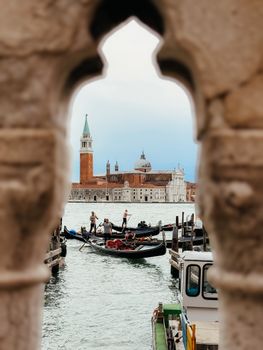 A gondola gliding along Venice's canal framed by a historic archway, with San Giorgio Maggiore in the backdrop.