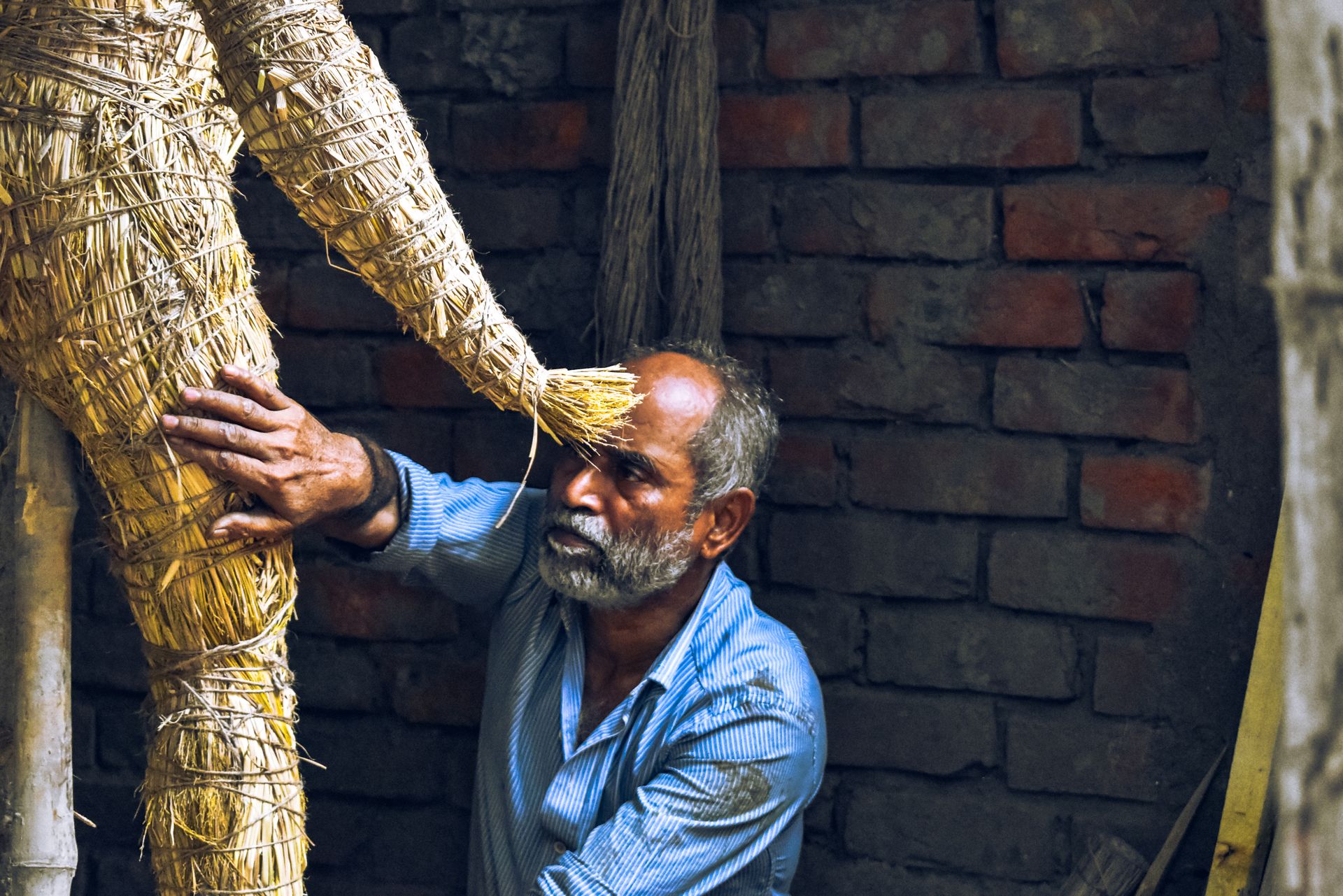 Artisan sculpting a straw idol in Kumartuli, Kolkata, capturing cultural craftsmanship.