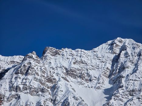 Breathtaking view of snow-covered mountain peaks under a clear blue sky.