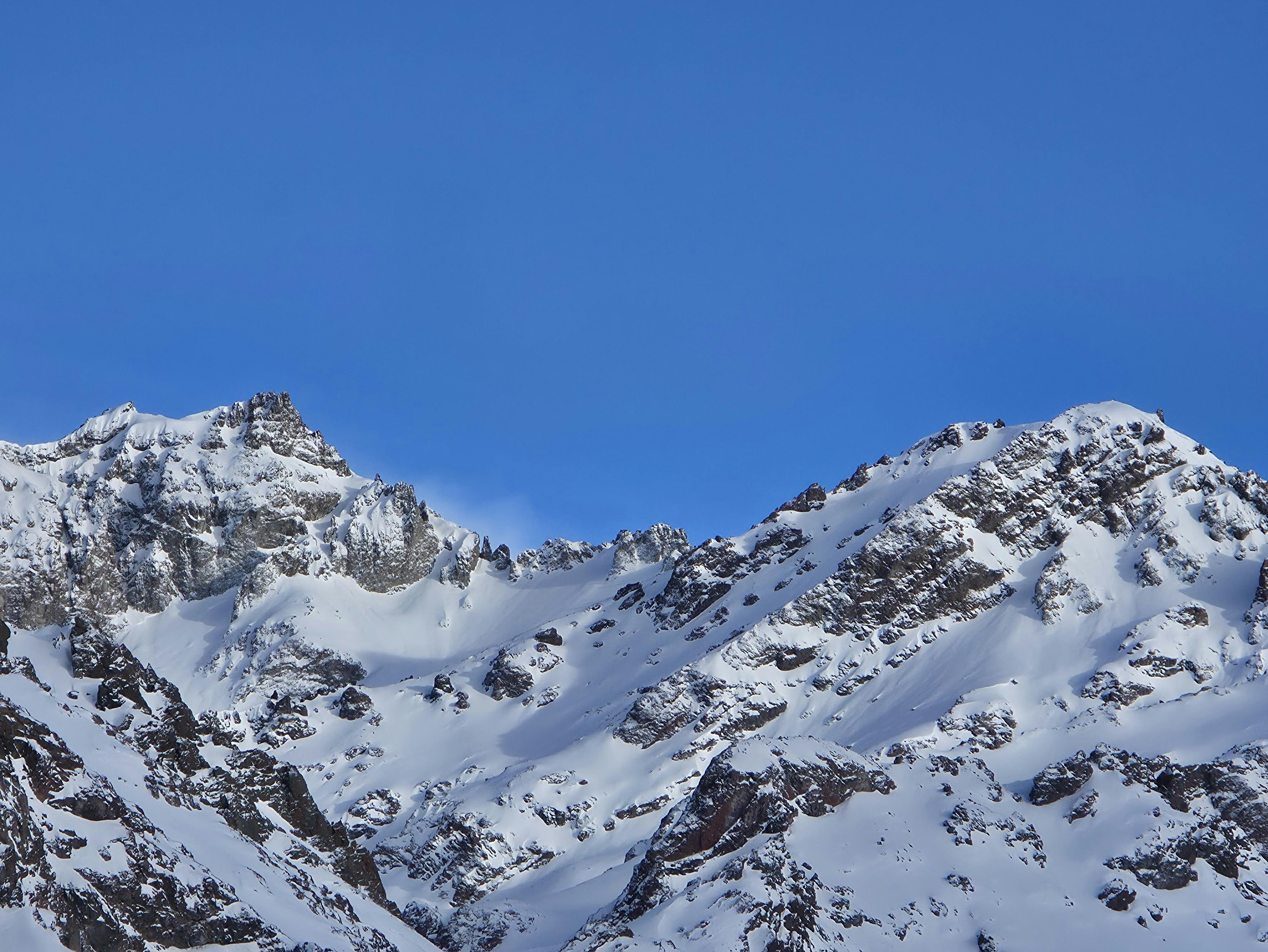 Majestic snow-covered mountain peaks against a clear blue sky, capturing the serene beauty of winter.