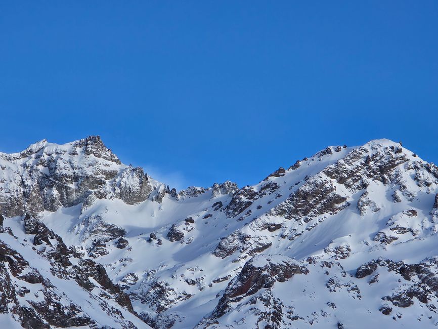 Majestic snow-covered mountain peaks against a clear blue sky, capturing the serene beauty of winter.