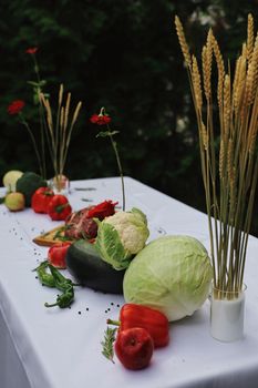 Colorful vegetables and flowers beautifully arranged on an outdoor table, ideal for natural decor themes.