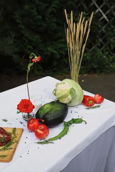 Beautiful arrangement of vegetables and flowers on a white table outdoors, perfect for autumn decor.