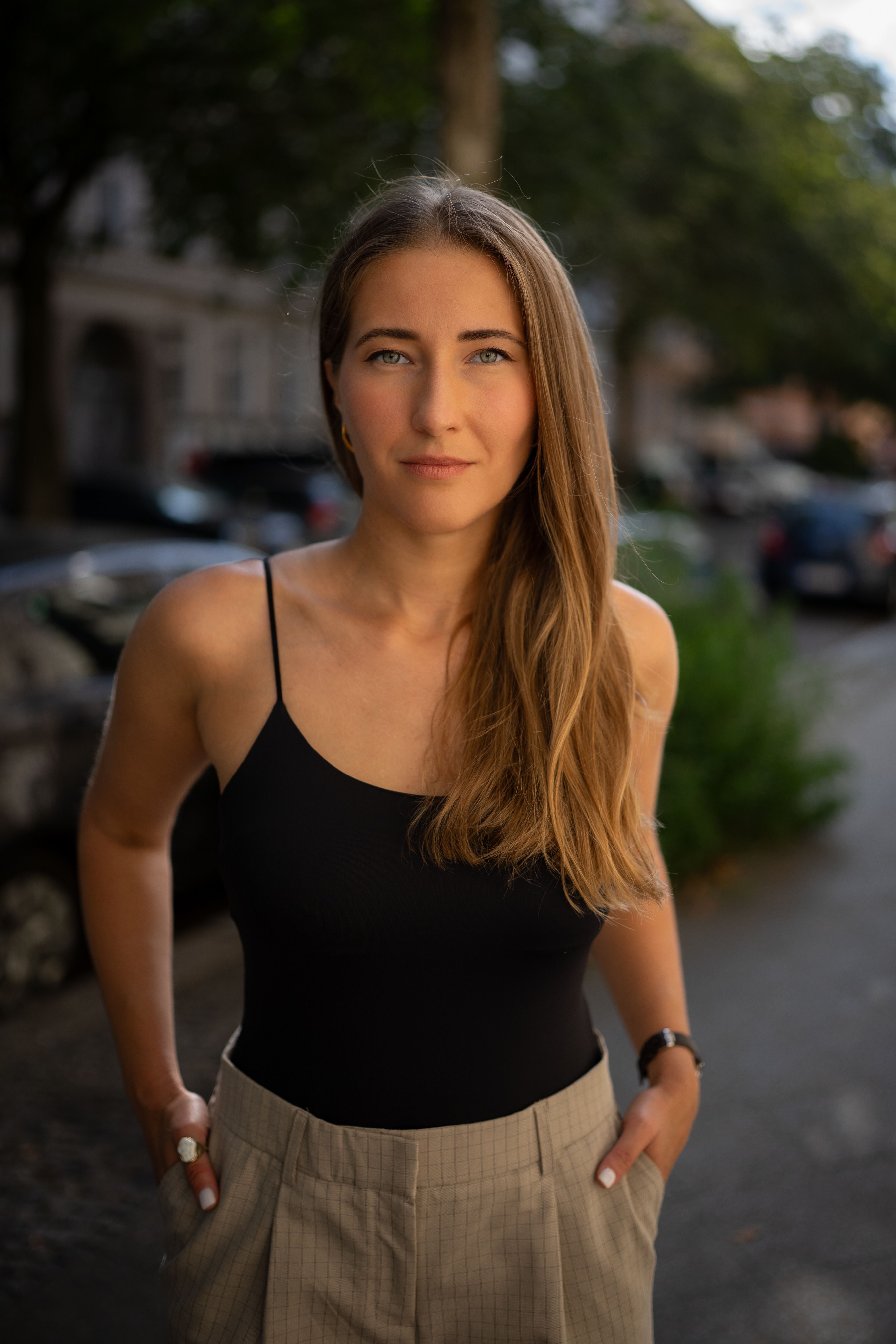 A fashionable woman poses confidently outdoors, showcasing her chic style and long hair.
