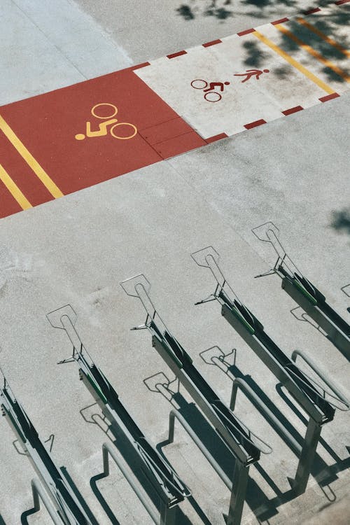 Aerial view of bicycle sign printed on asphalt road and empty rack parking lots on sunny day