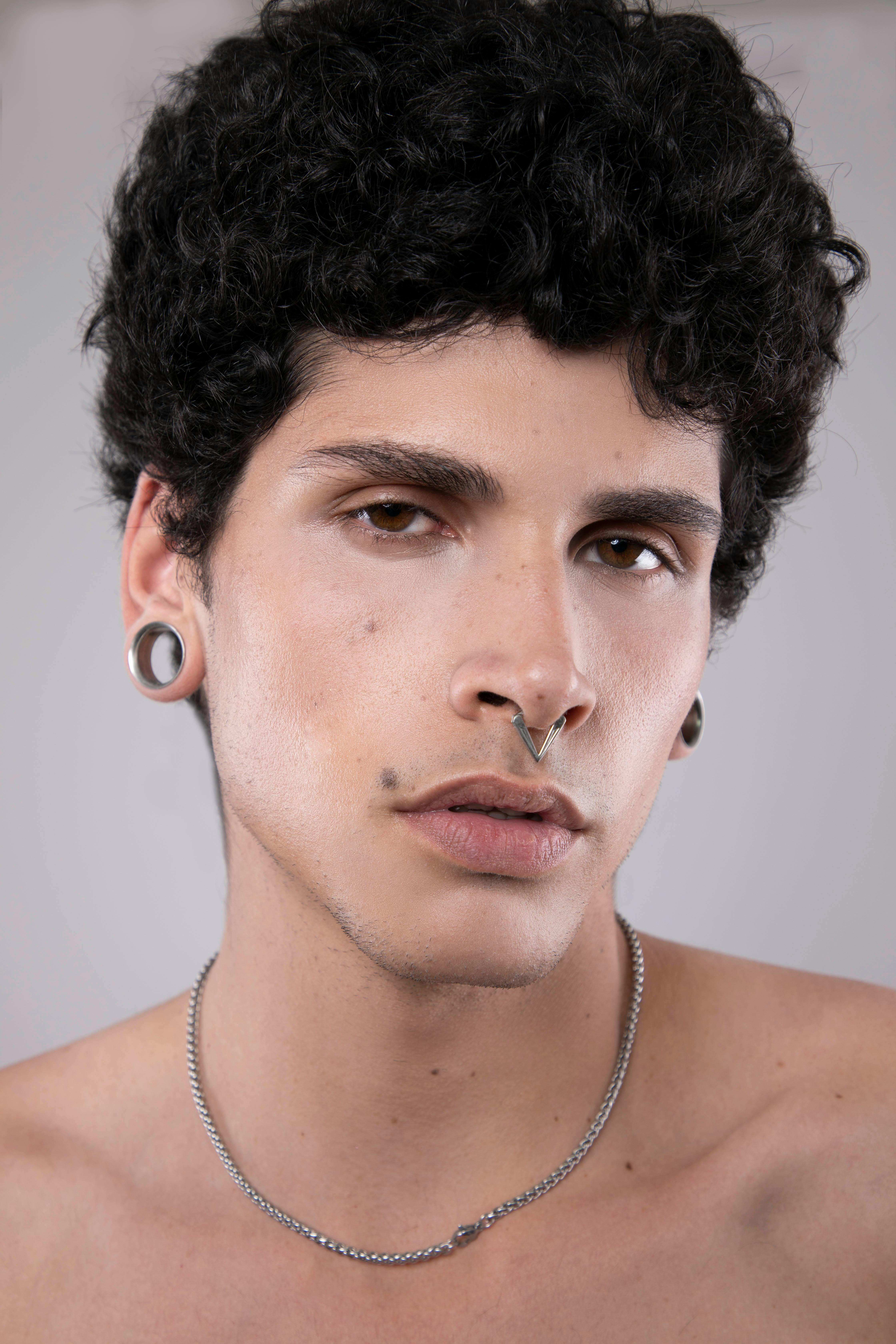 Close-up portrait of a young man with ear gauges and septum piercing in Mexico City.