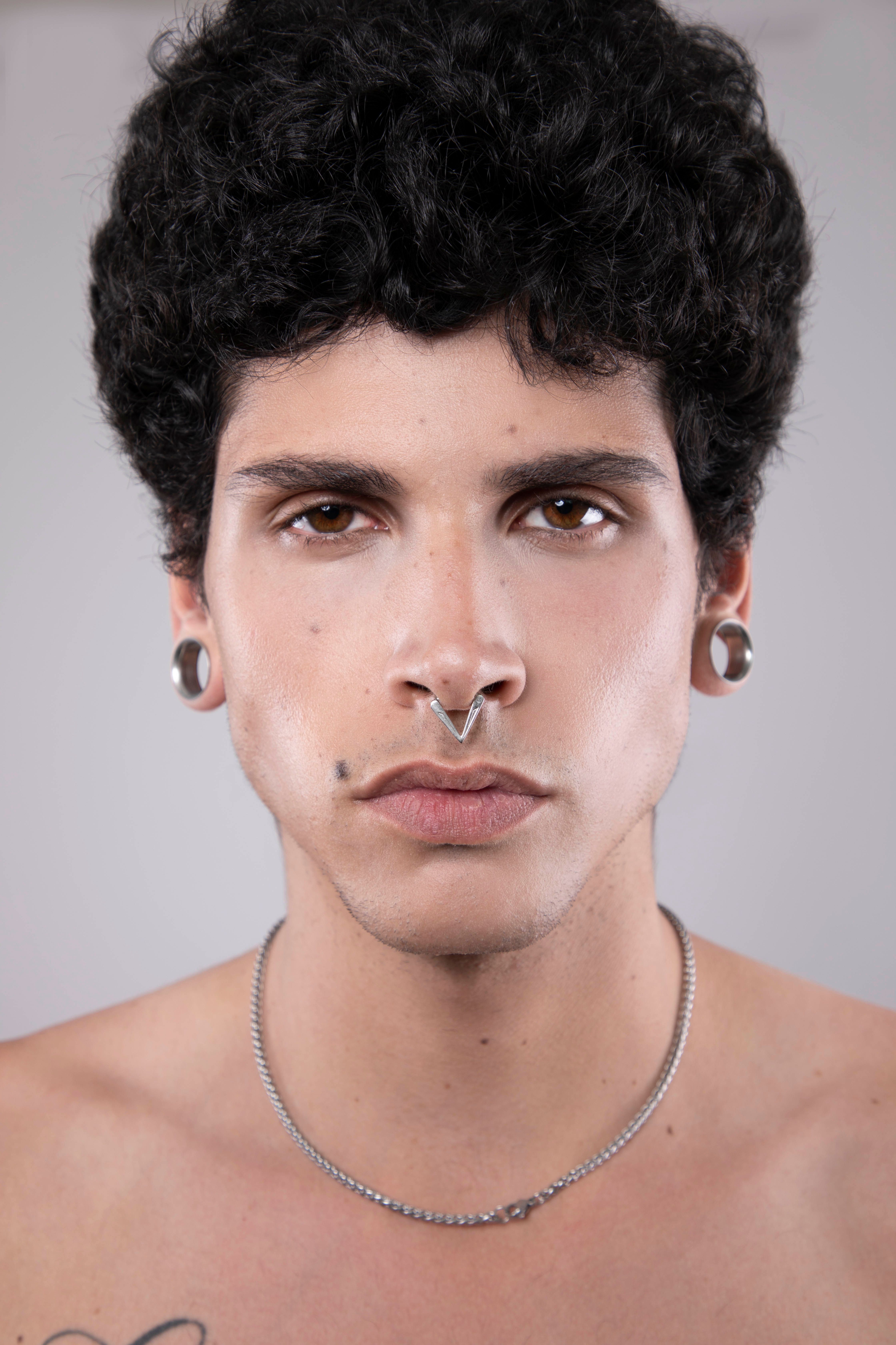 Close-up male portrait showcasing piercings and intense gaze.