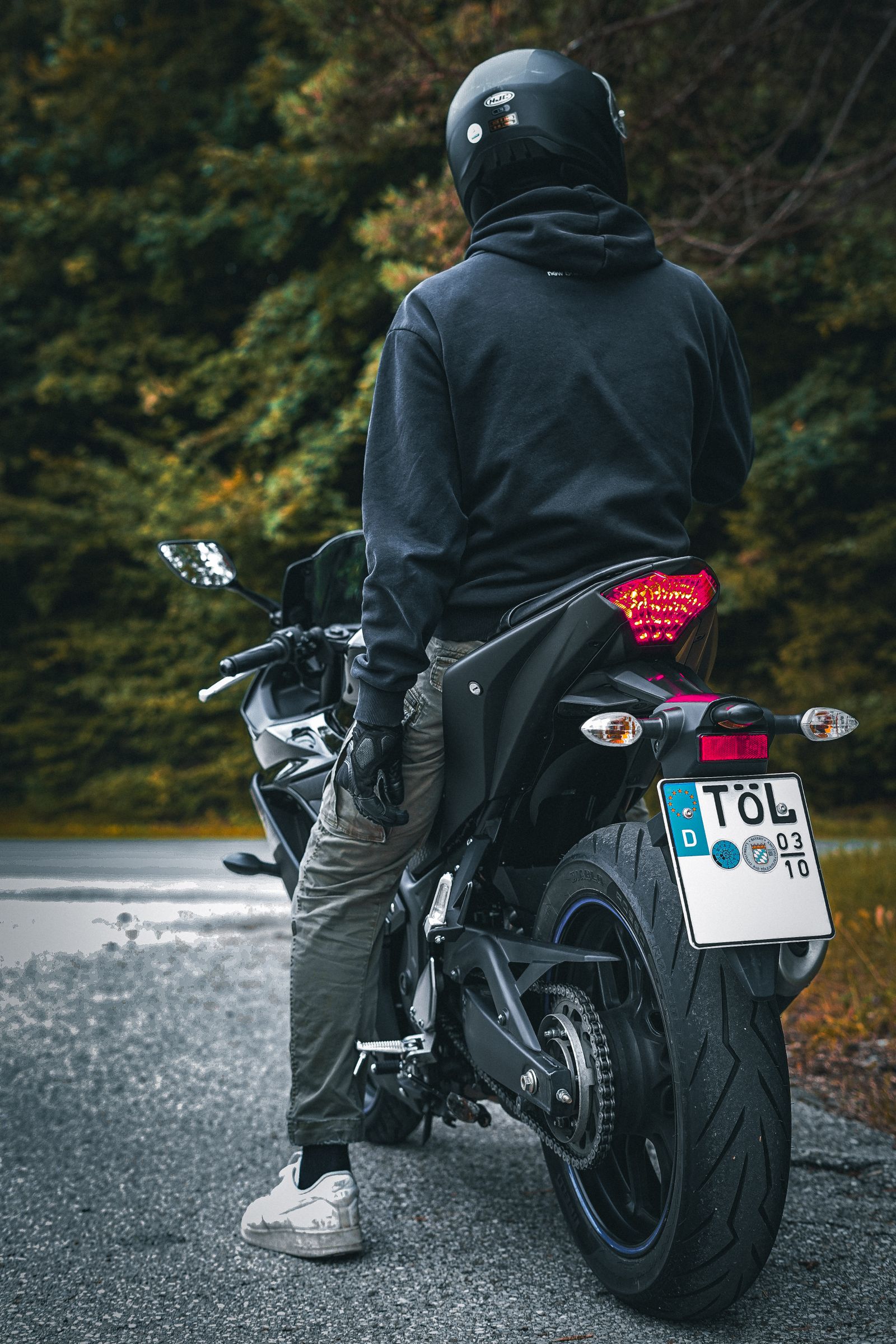 Jeune motard fait une pause en forêt, incarnant l'aventure et la liberté