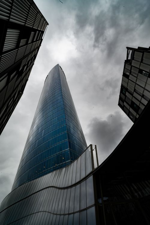 Free A stunning view of a modern skyscraper in Bilbao, Spain, set against a dramatic cloudy sky. Stock Photo