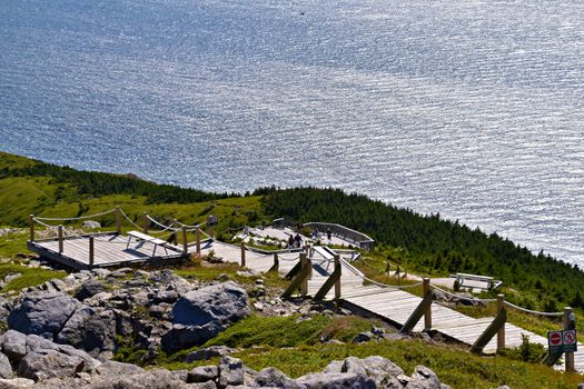 Wooden boardwalk trails on a rocky hill with ocean view in Nova Scotia, Canada.