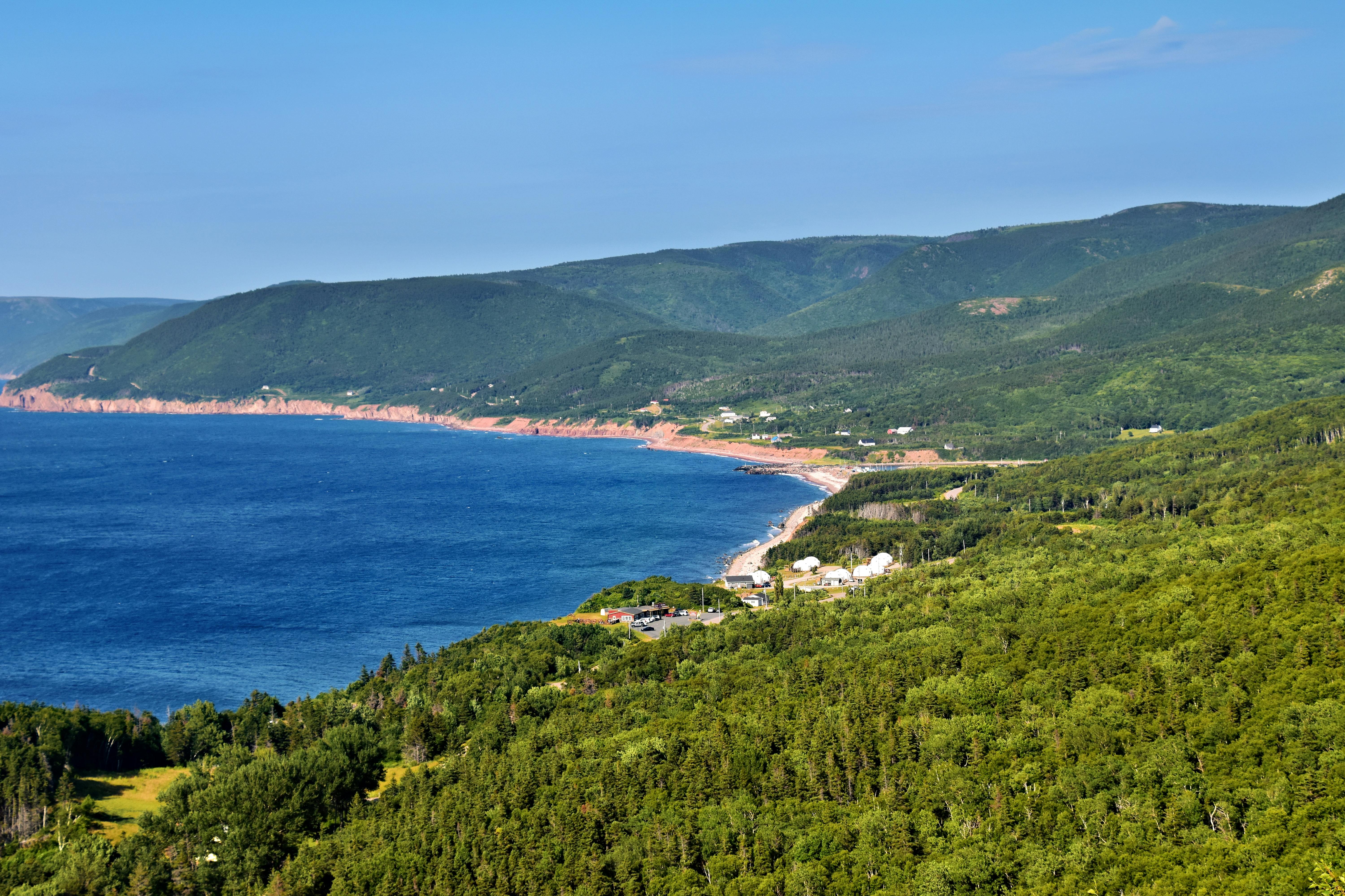A stunning aerial view of Cape Breton's lush green landscape meeting the vibrant Atlantic Ocean.