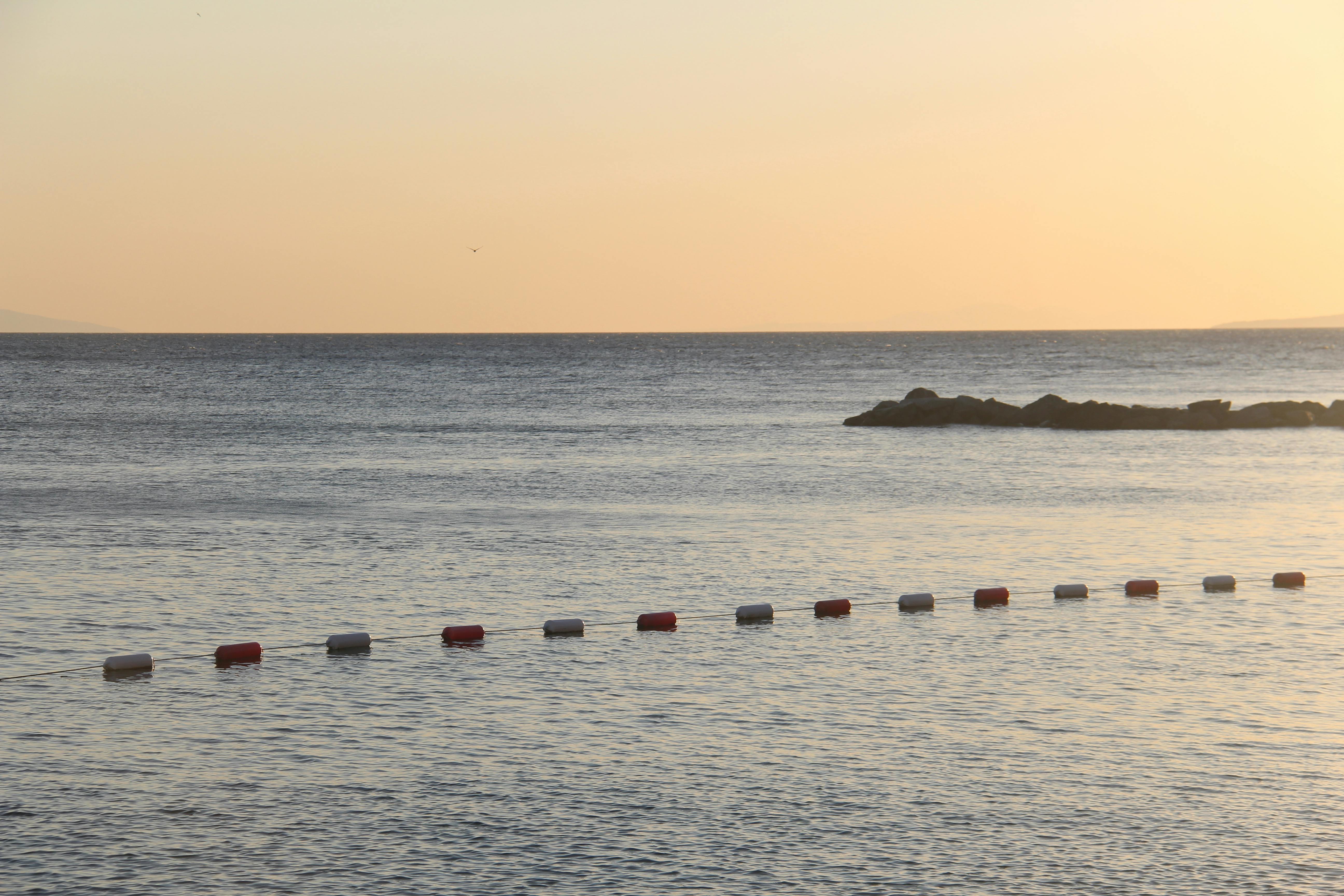 Tranquil sunset scene with floating buoys and gentle waves by the seashore.