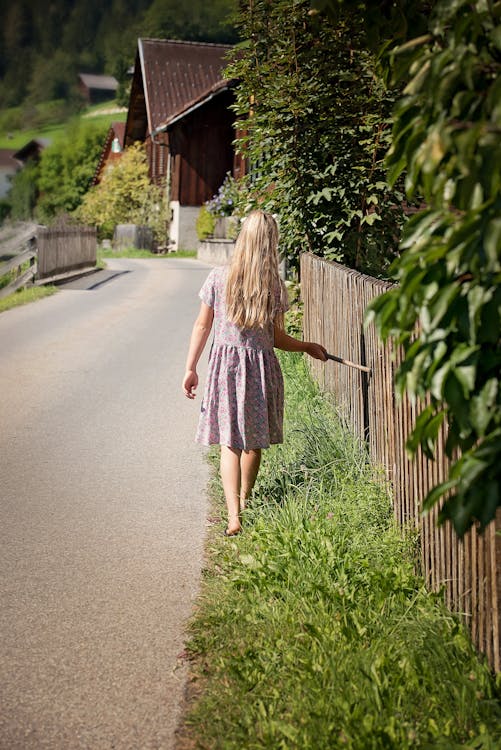 무료 낮 동안 푸른 잔디 필드를 따라 걷는 흰색과 보라색 드레스 소녀 스톡 사진