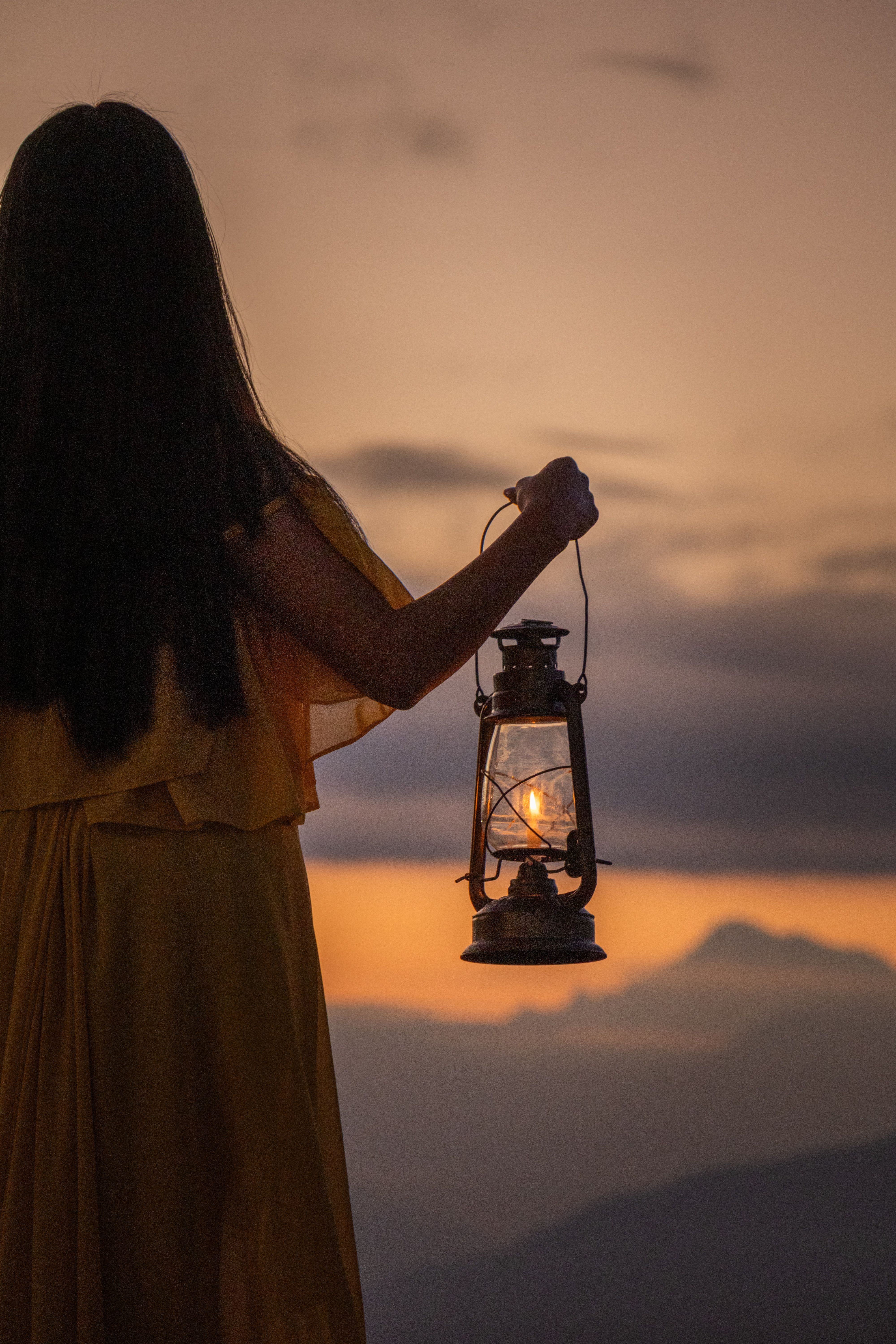 Silhouette of Woman with Lantern at Sunset · Free Stock Photo