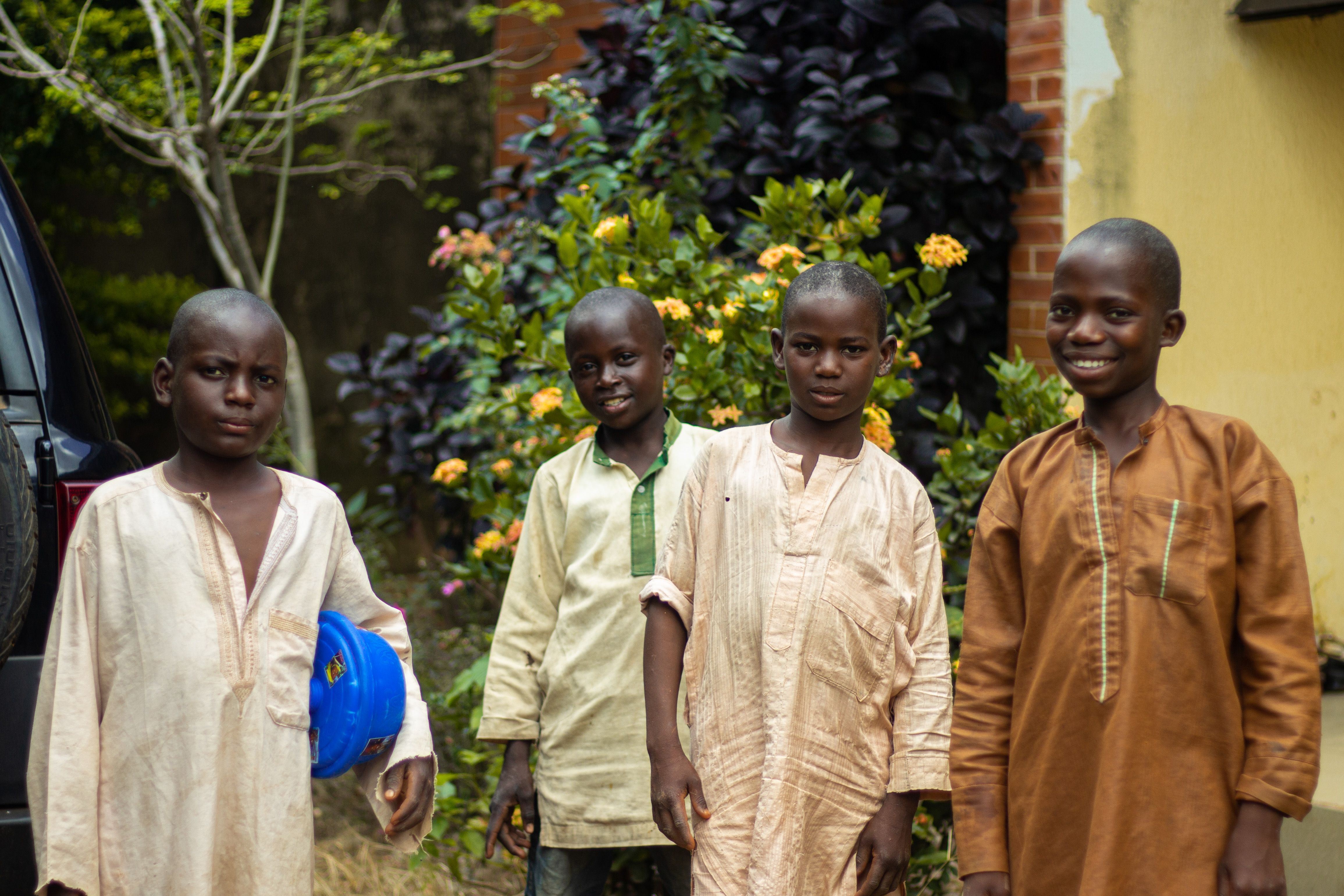 Dark-skinned Nigerian civil servant family — father in a plain office shirt and mother in adire fabric — seated around a wooden dining table in a modest Lagos home, sharing a large pot of jollof rice and fried plantain, natural window light, photorealistic