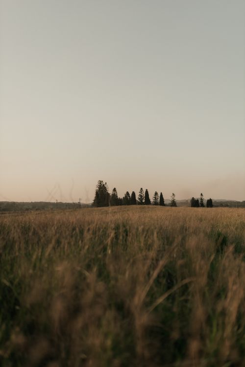 Free Beautiful sunset over a serene countryside landscape with distant trees. Stock Photo