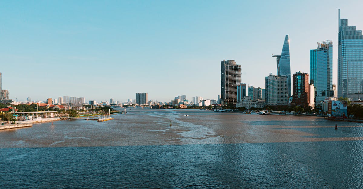Skyline of Ho Chi Minh City along the Saigon River showcasing modern skyscrapers under a clear blue sky.