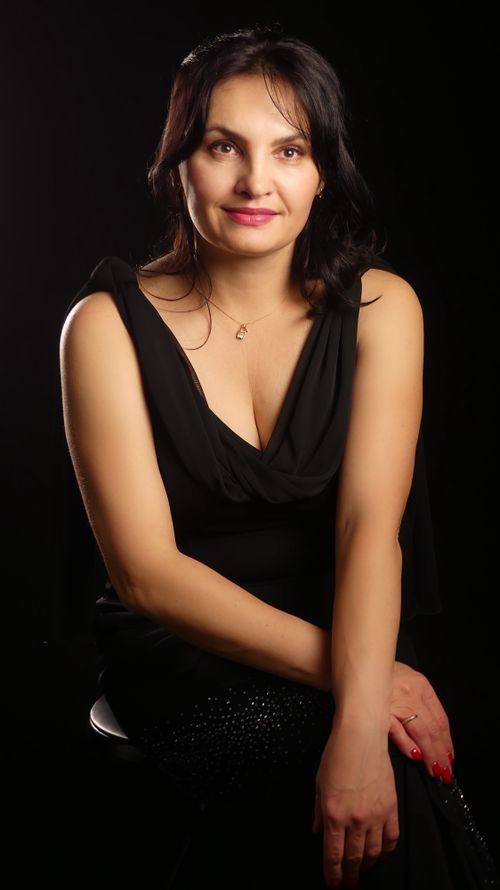 Free Elegant portrait of a woman in a black dress against a dark background. Stock Photo