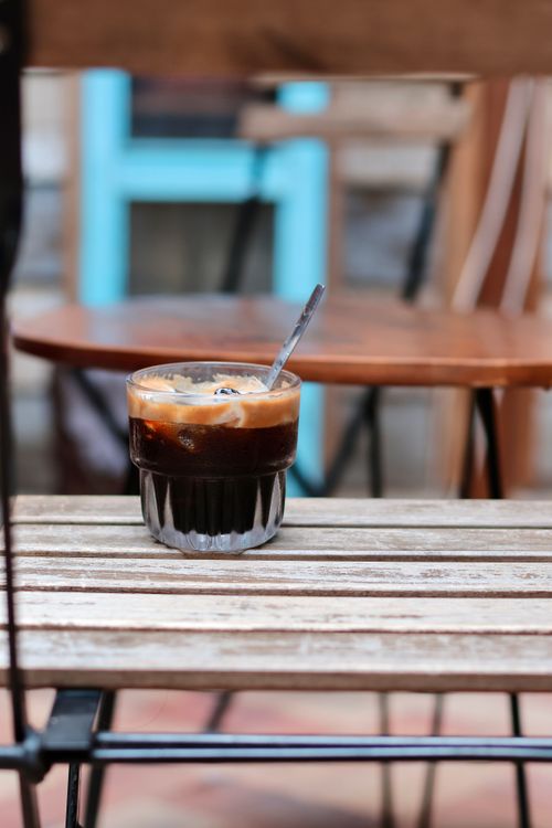Free Refreshing cold brew coffee served on a wooden outdoor table in a cafe setting. Stock Photo