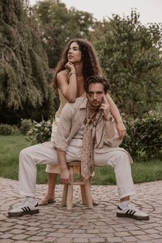 Fashionable couple posing in a lush garden with vintage flair, showcasing modern romantic style.