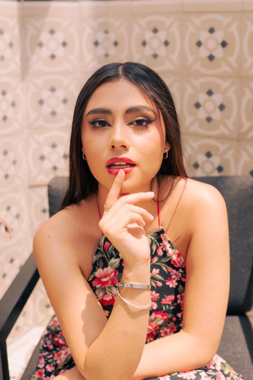 Free Woman posing outdoors in Mexico, wearing a floral dress and seated on a chair, expressing confidence. Stock Photo