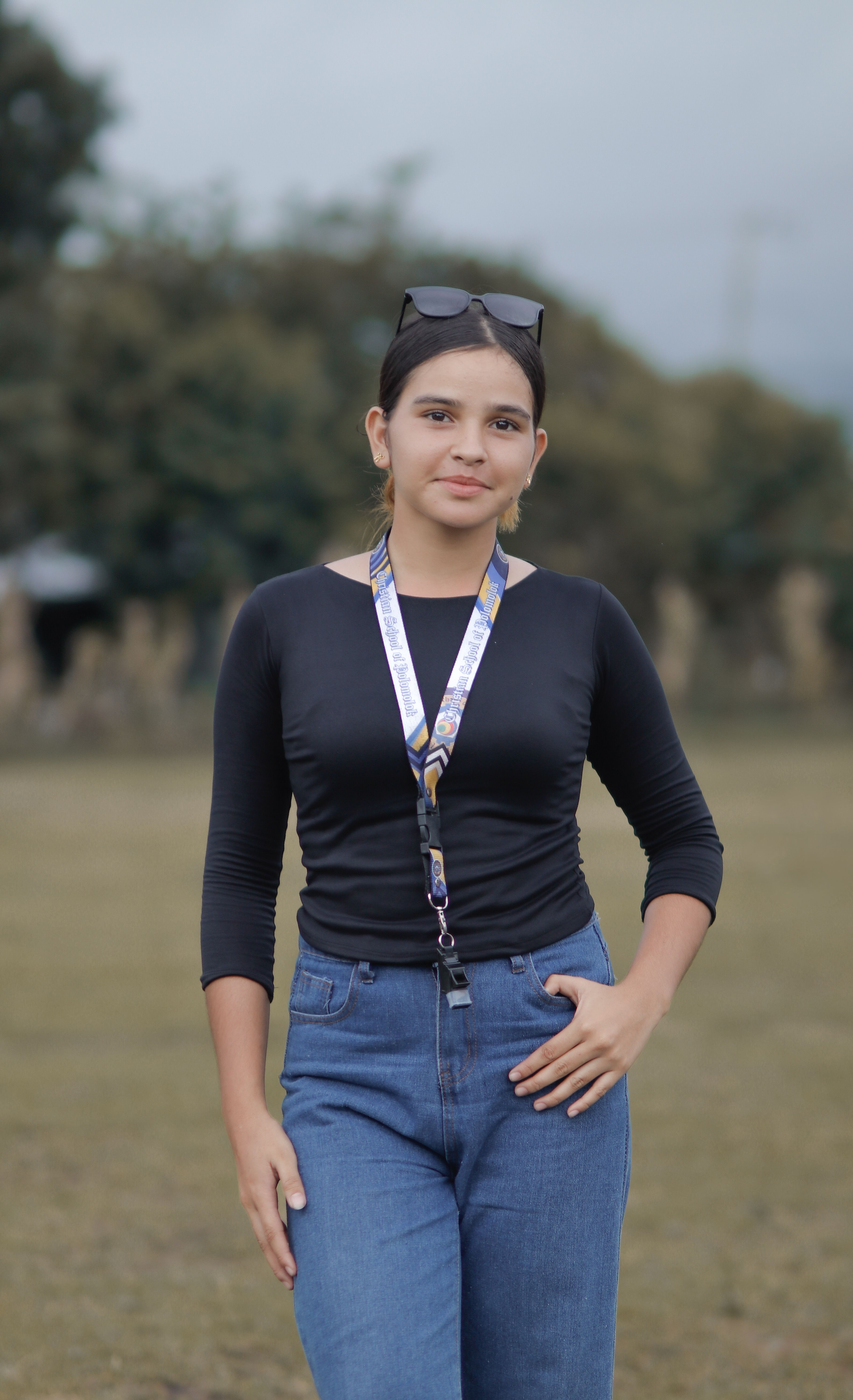 Portrait of a young woman standing outdoors in casual attire, showcasing confidence.