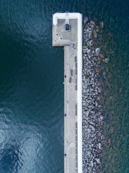 Drone shot of a lighthouse pier extending into the blue water in Jönköping, Sweden.
