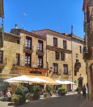 Cafes and historic architecture create a charming street scene in a European village.