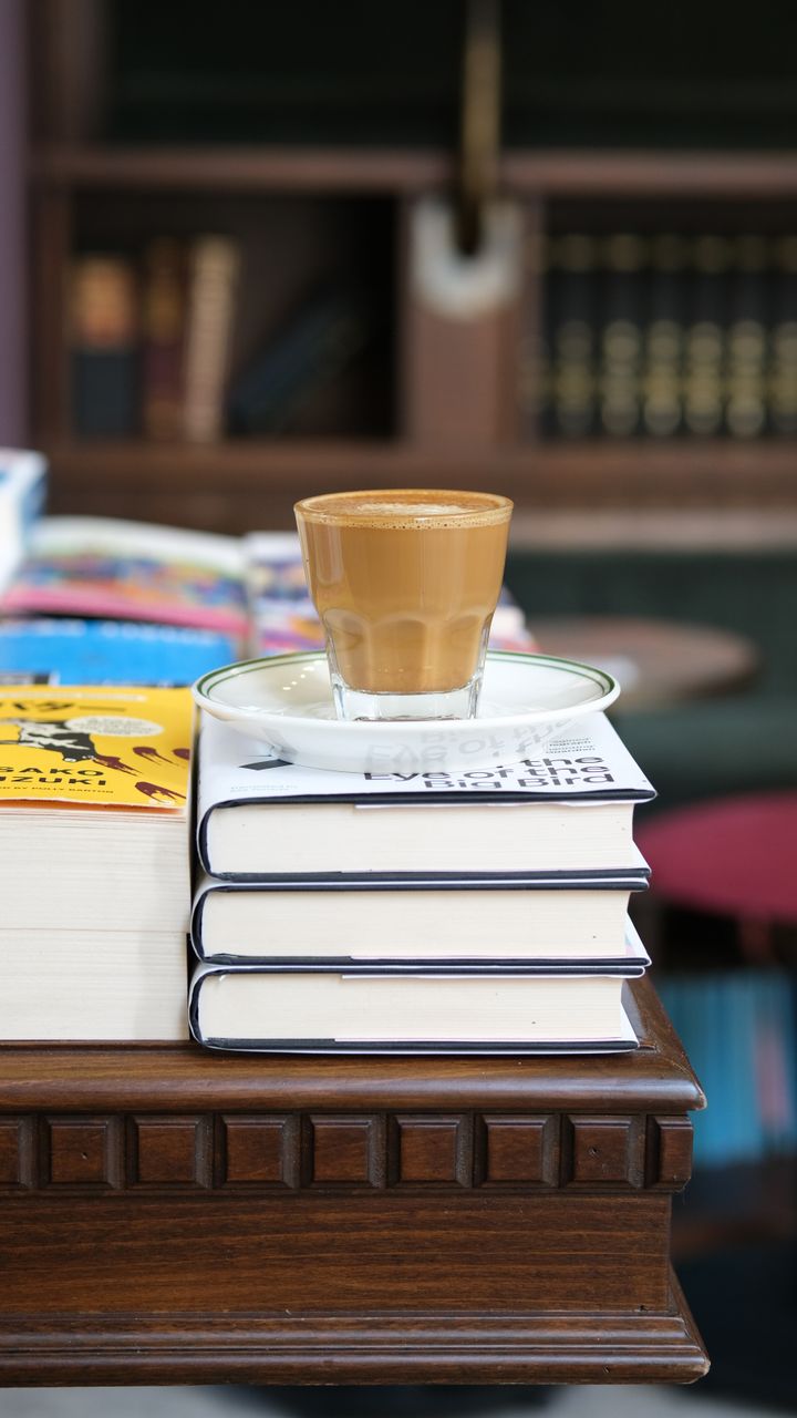 stacked hardcover books in a corner used as a temporary small coffee bar surface