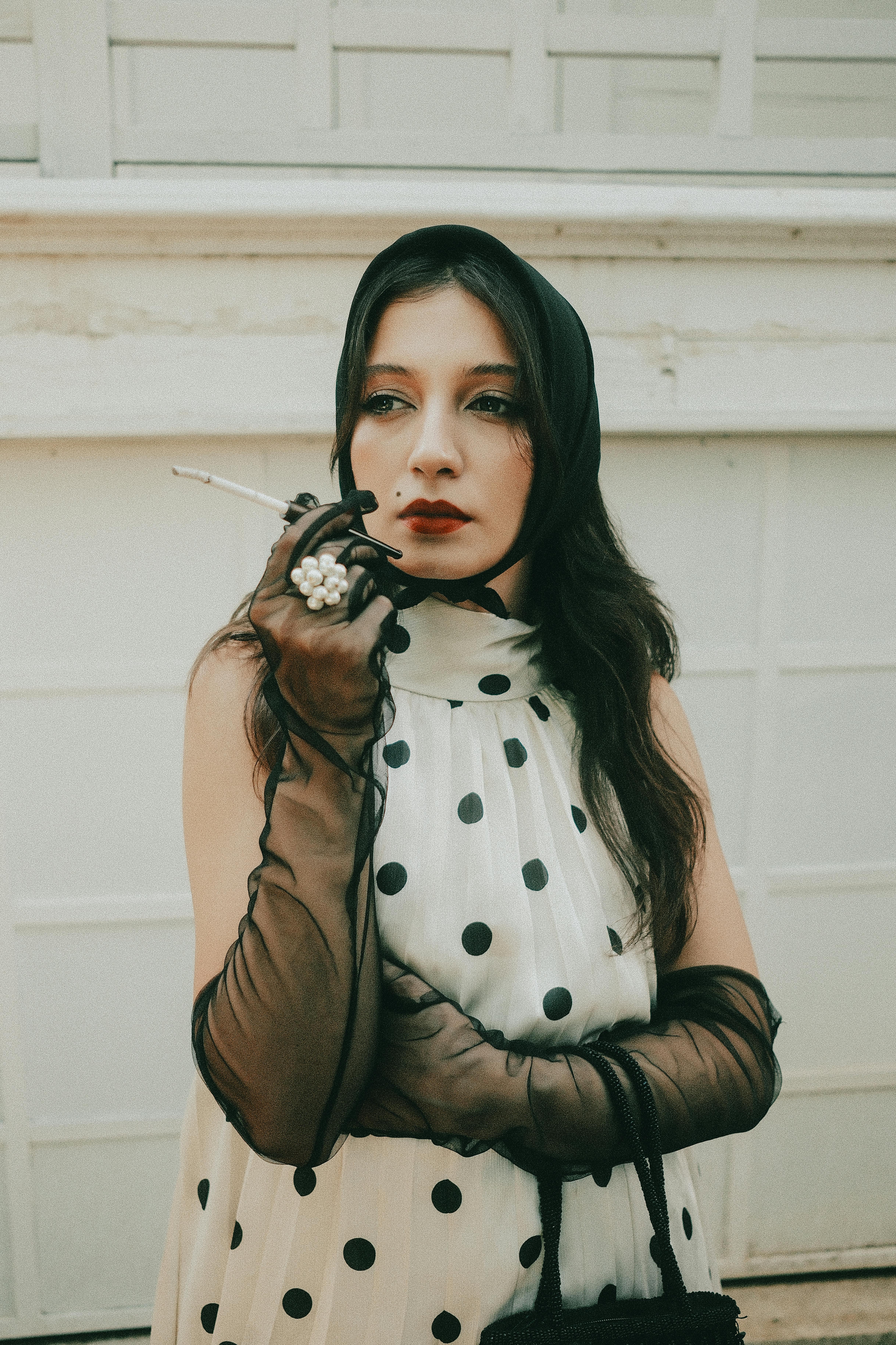 Miễn phí Người phụ nữ sành điệu trong trang phục cổ điển với chấm bi đen và găng tay, đứng bên ngoài. Ảnh lưu trữ