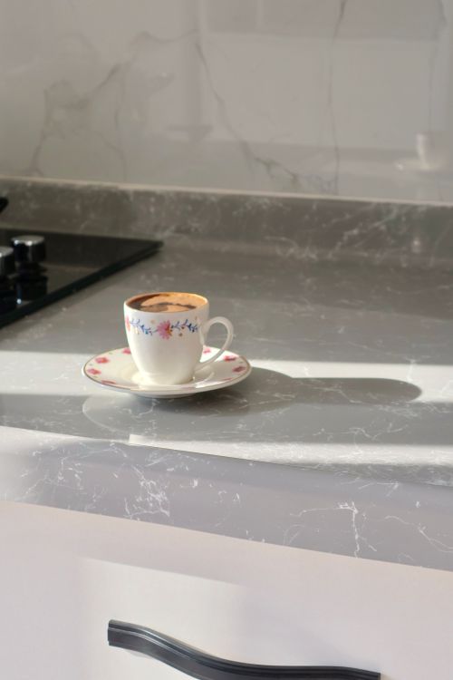 Free A delicate floral teacup filled with coffee on a sunny marble countertop. Stock Photo