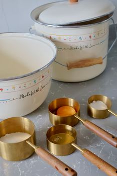 Stylish vintage cookware with brass measuring cups on a marble countertop, ideal for baking aesthetic.