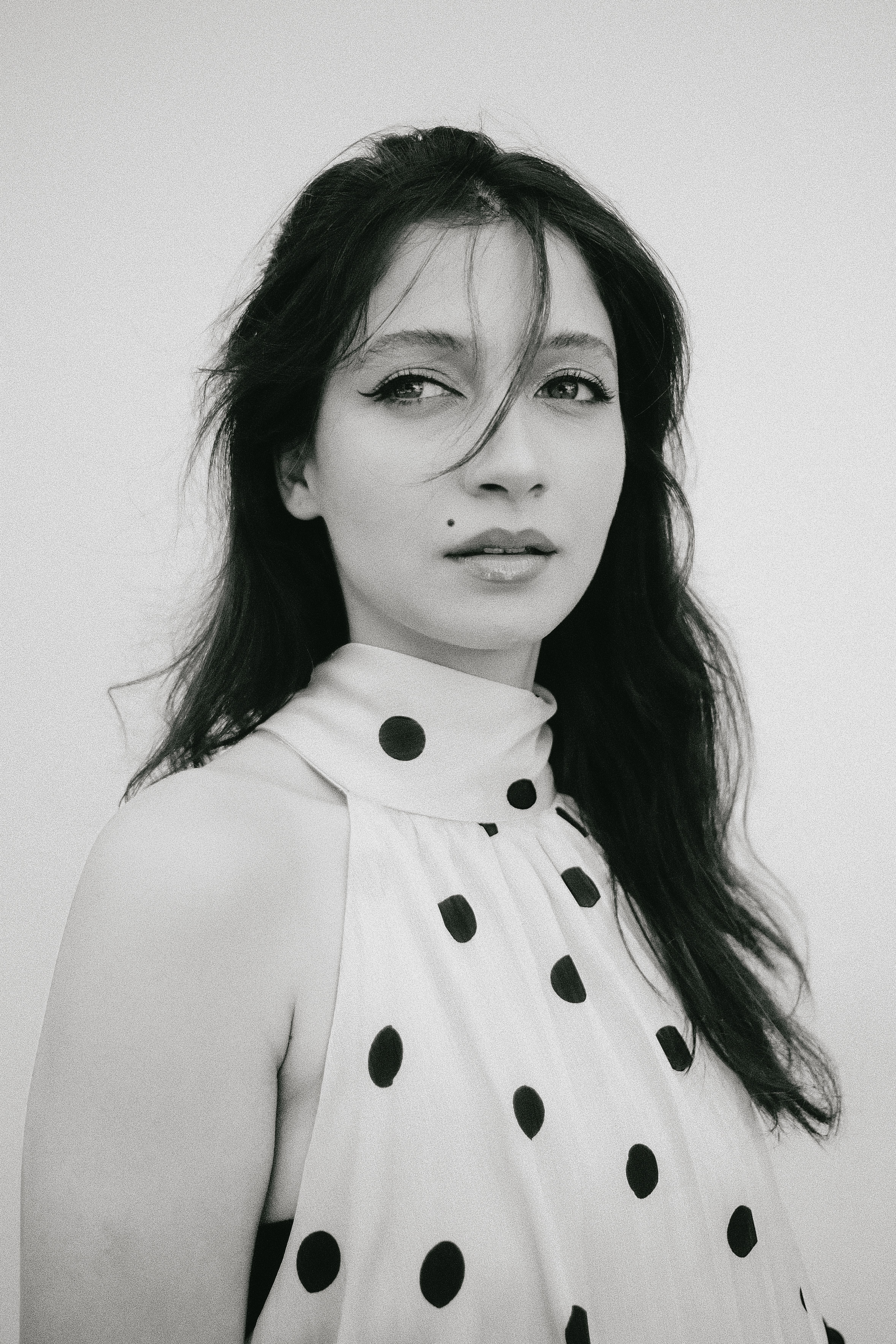 Black and white portrait of a woman in polka dot dress exuding elegance.