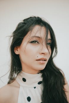 Stylish portrait of a young woman with long hair and polka dot dress, exuding confidence and elegance.