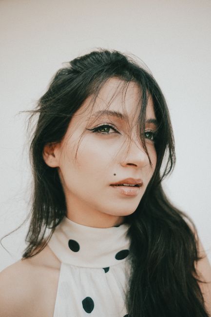 Stylish portrait of a young woman with long hair and polka dot dress, exuding confidence and elegance.