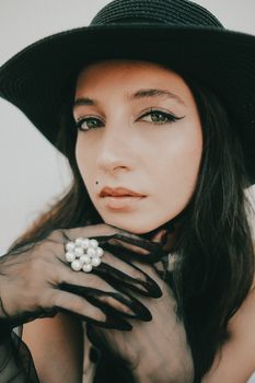 Stylish woman wearing a vintage hat and gloves, exuding timeless elegance and sophistication.