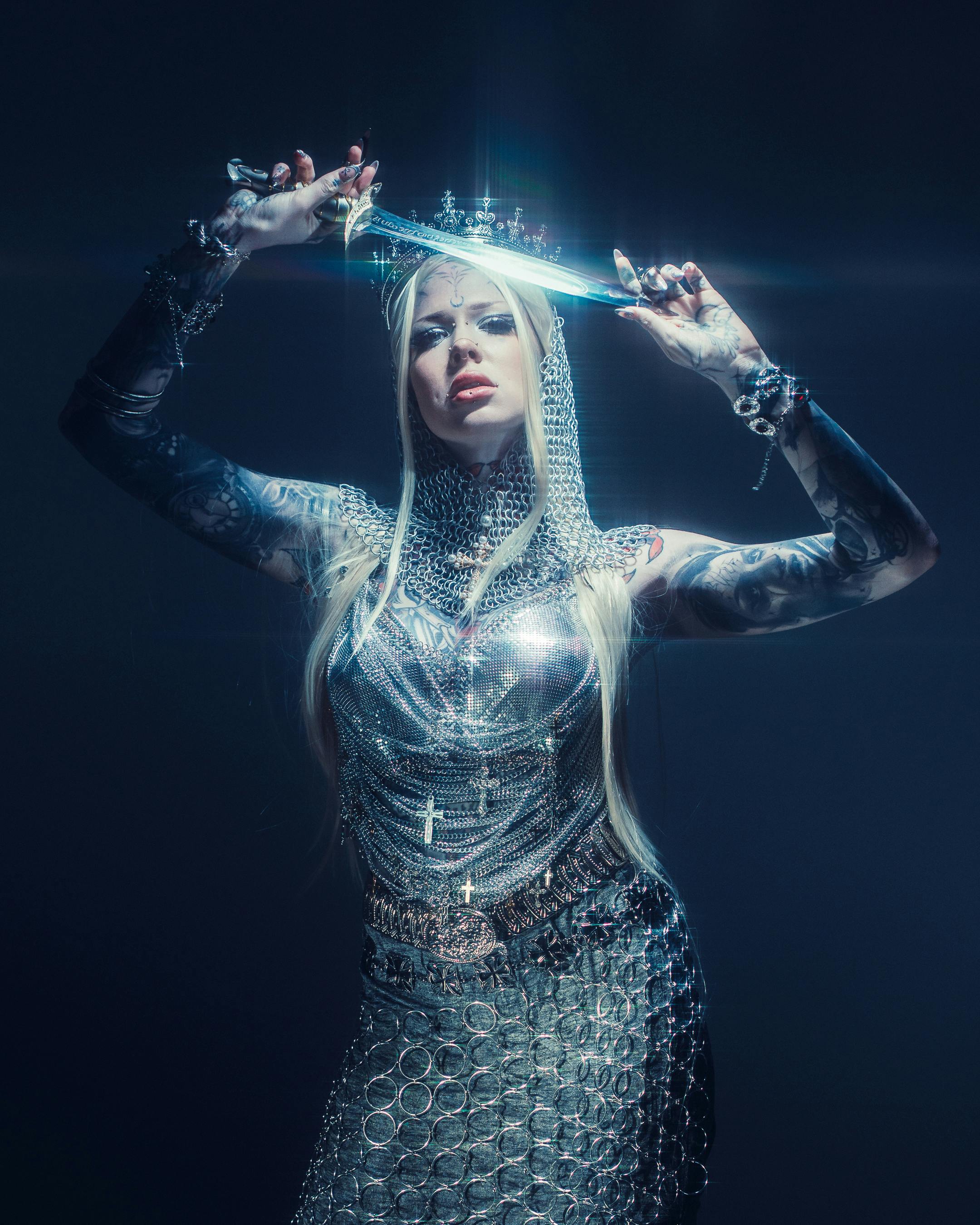 Gratis Et dramatisk portrett av en kvinne i ringbrynje som holder et sverd, som utstråler fantasi og motestil. Arkivbilde