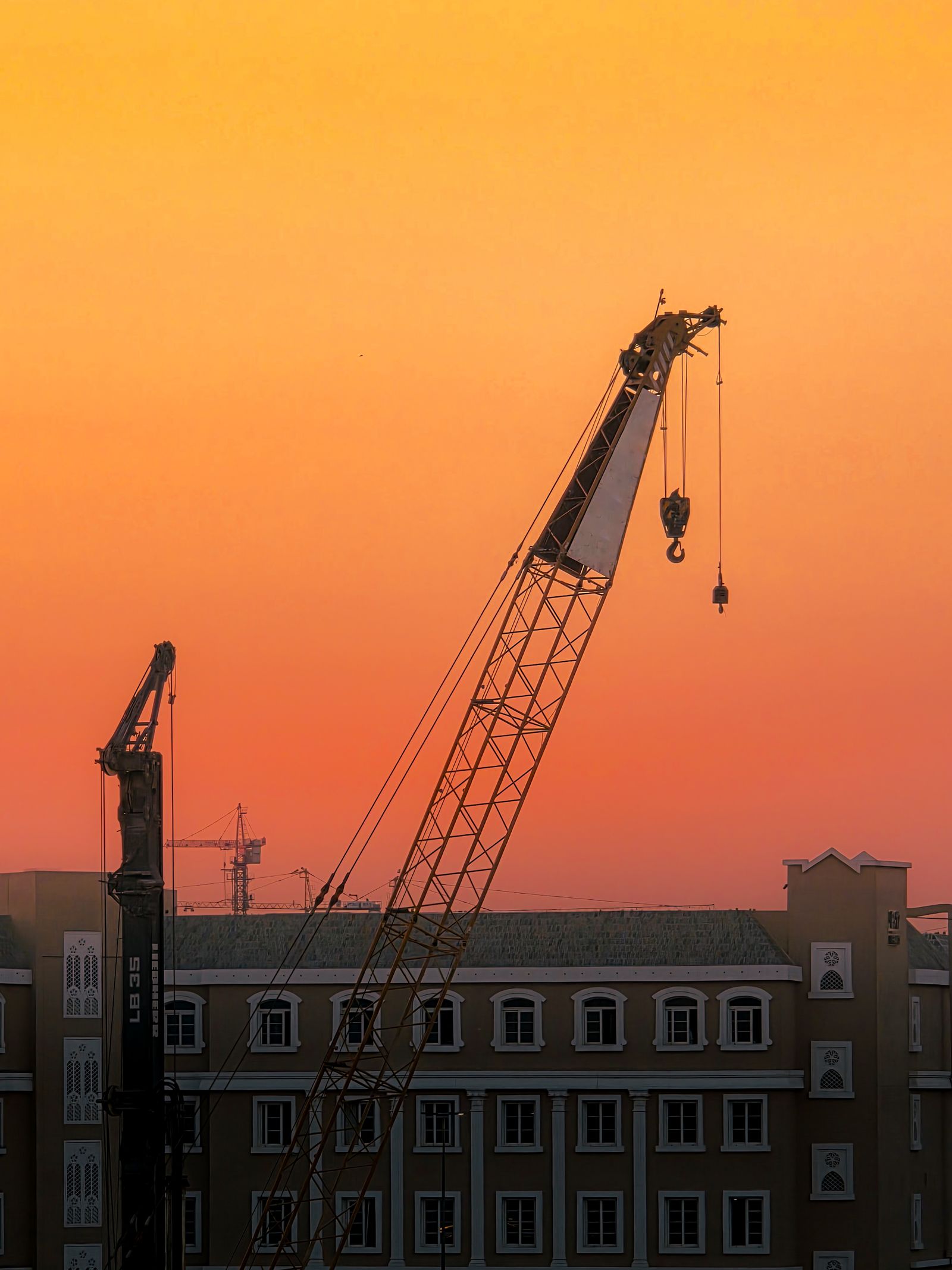 Construction crane silhouetted against a sunset sky