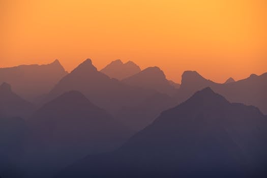 Beautiful silhouette of the Austrian Alps at sunset with orange sky.